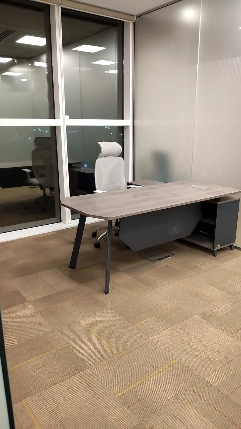 Executive desk and white ergonomic chair in a finished office with glazed partitions