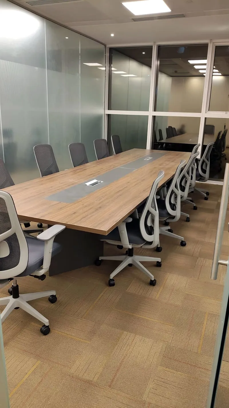 Meeting room with a long timber table, mesh chairs and glass partitions