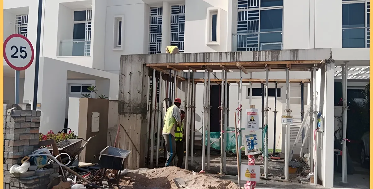 Villa entrance under renovation, with temporary props and workers on site