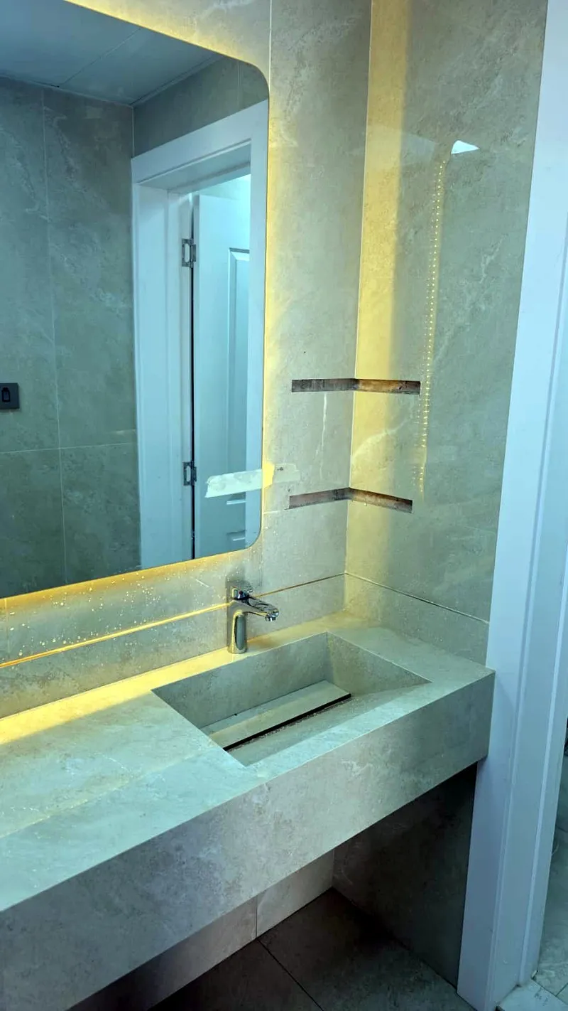 Stone vanity and backlit mirror in the renovated bathroom
