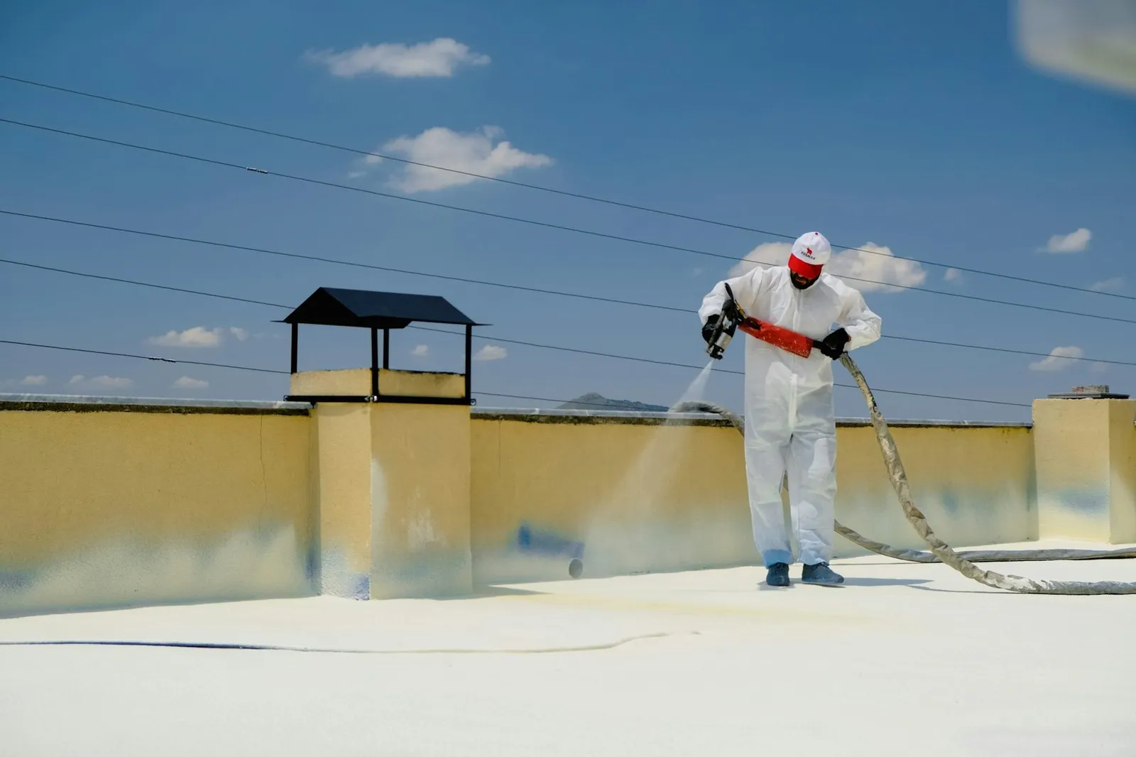 Technician applying sprayed waterproofing membrane to a roof surface